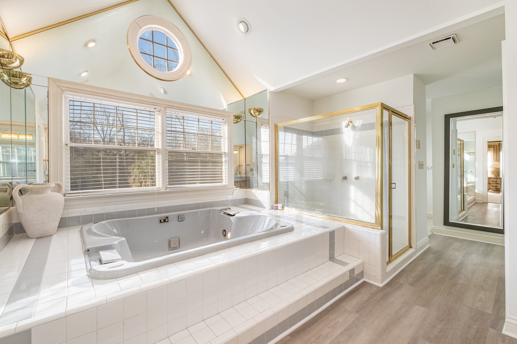 Bathroom with white and gold accents, glass shower, jacuzzi tub. Image is pre-renovation