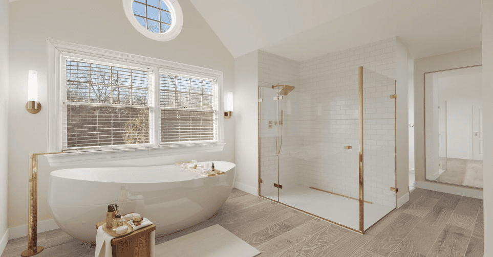 Modern updated bathroom with a standalone tub, shower, and white and gold accents