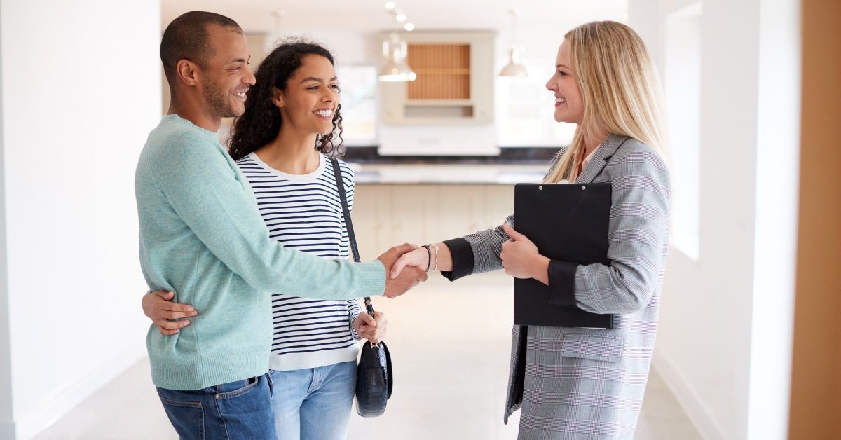 A couple shaking hands with a professional carrying a clipboard