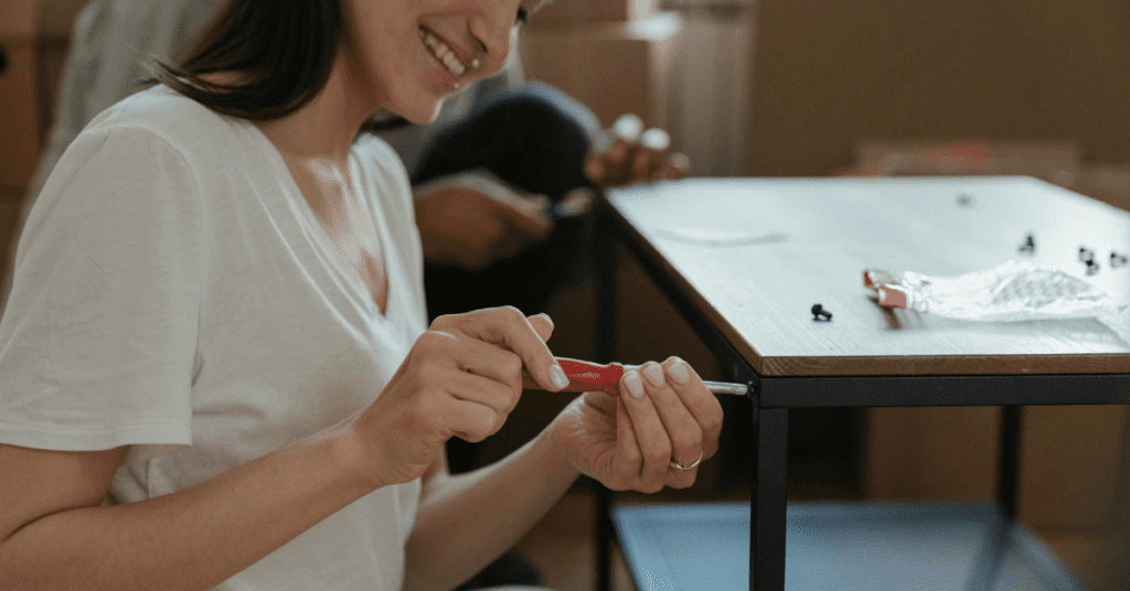 Woman screwing a table together by hand.