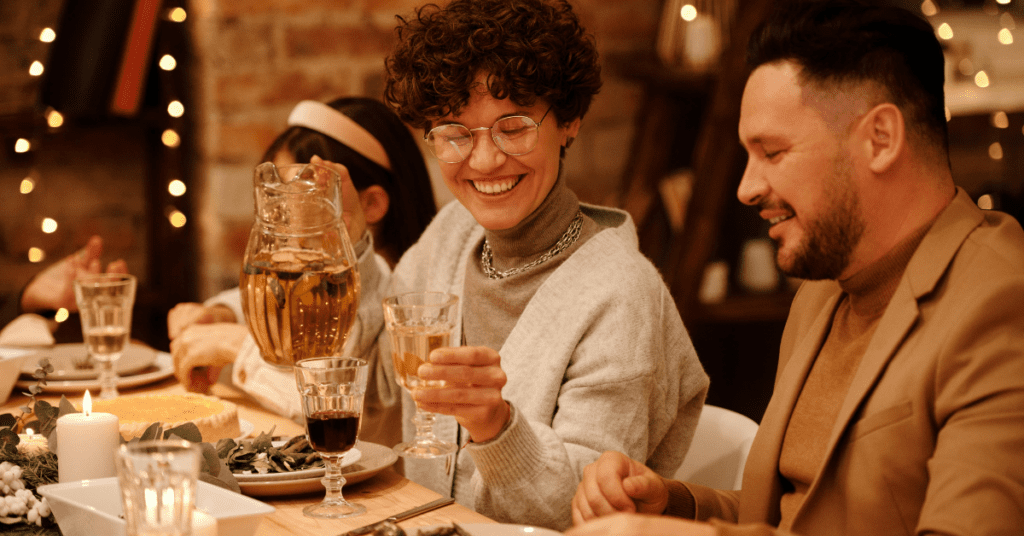 A man, woman, and child smiling while sitting around a holiday dinner table.