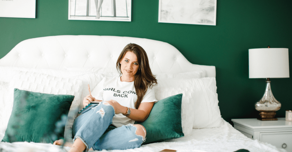 Jamie Milam sitting in her newly decorated room after divorce; the walls are green with white accents and posters hung up