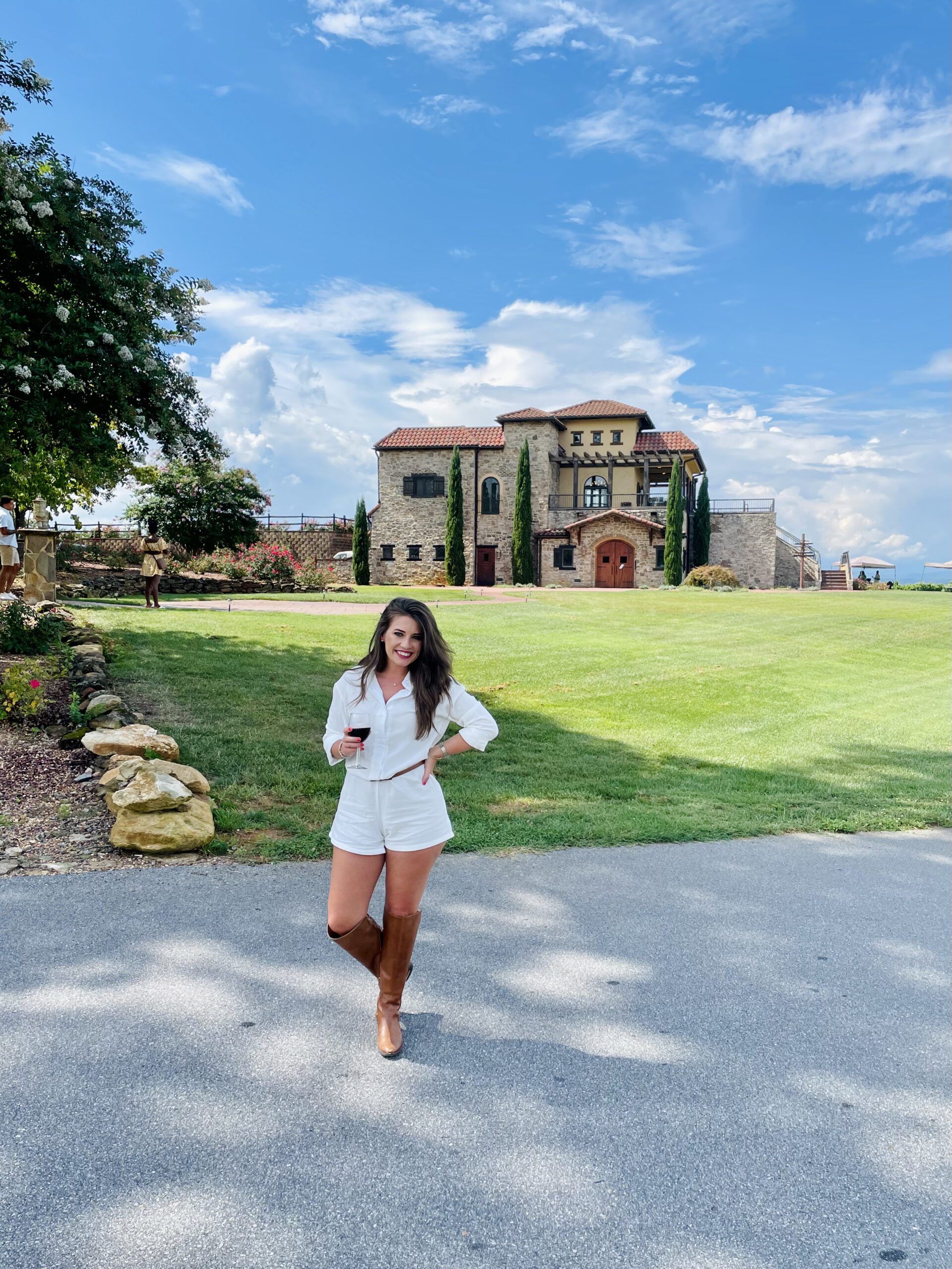 Woman standing with a glass of wine in front of a beautiful Raffaldini Vineyards