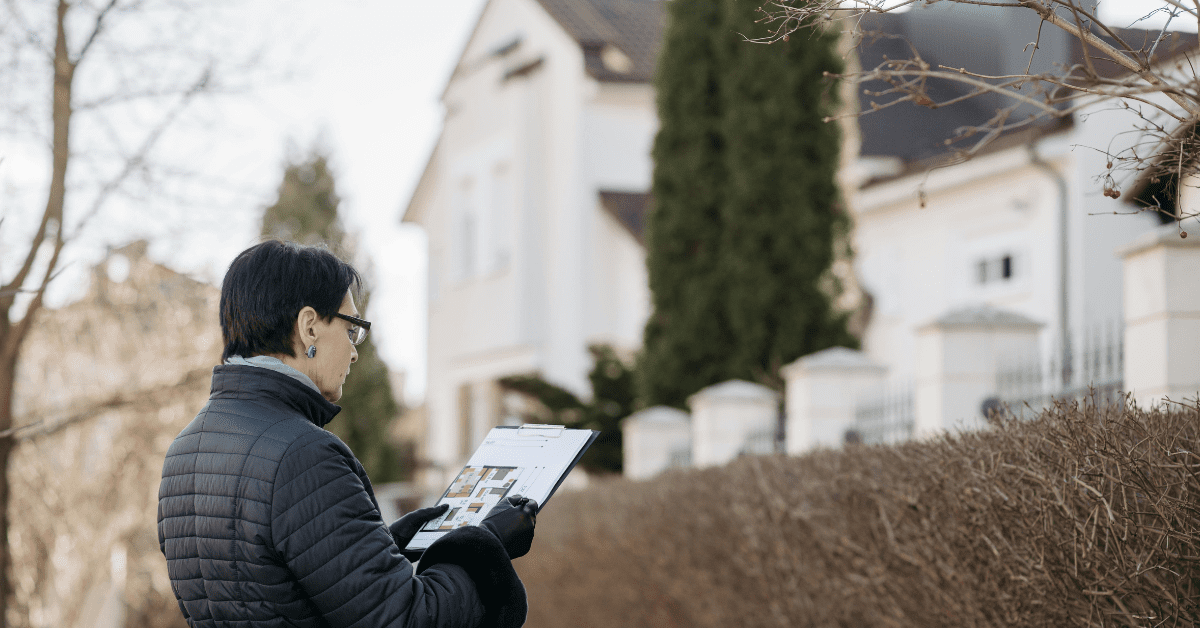 Woman holding a clipboard looking at a house for a property survey