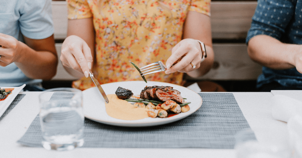 Image of a woman eating a steak dinner