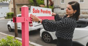Image of a Realtor hanging a "Sale pending" sign