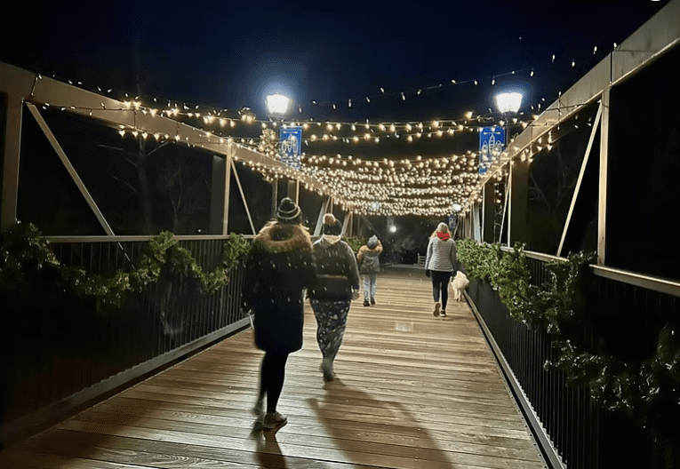 People walking on a bridge with holiday lights in Cramerton