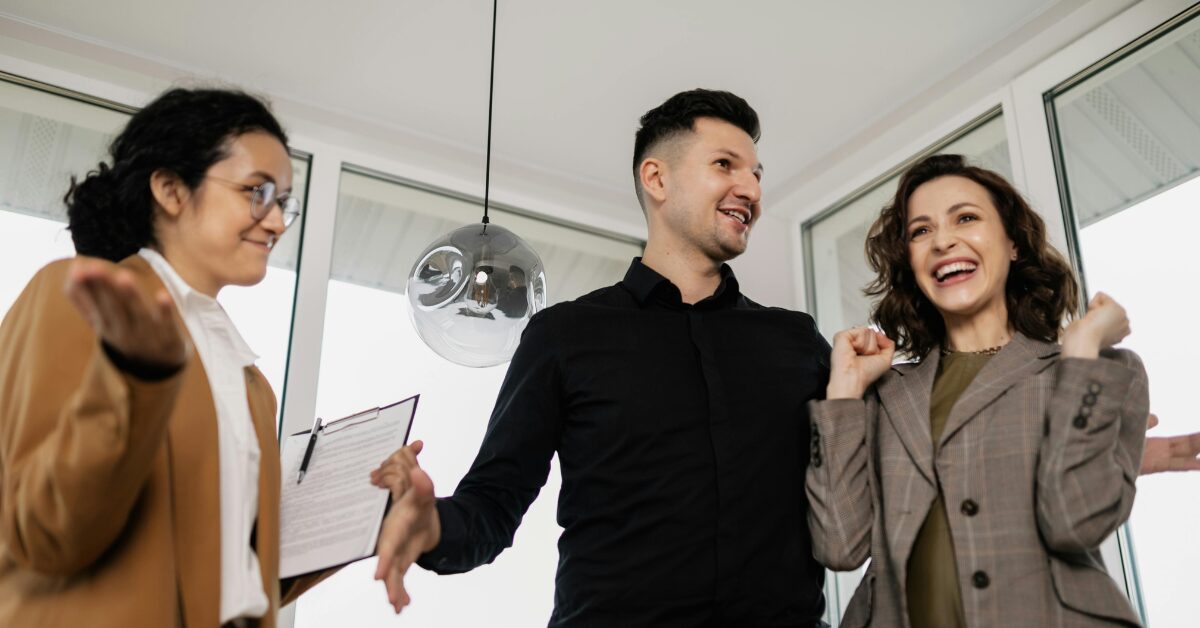 A real estate agent carrying a clipboard and showing a couple their new home