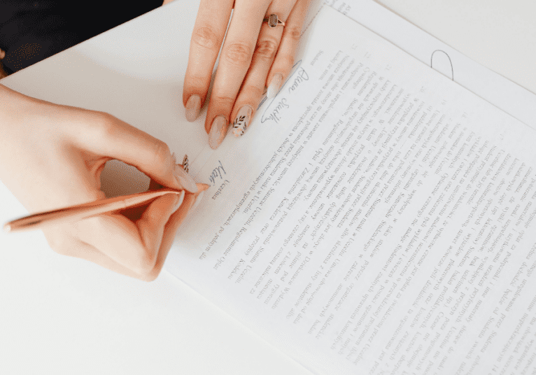 Woman signing paperwork with a pencil.