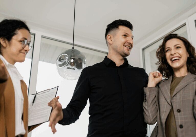 A real estate agent carrying a clipboard and showing a couple their new home