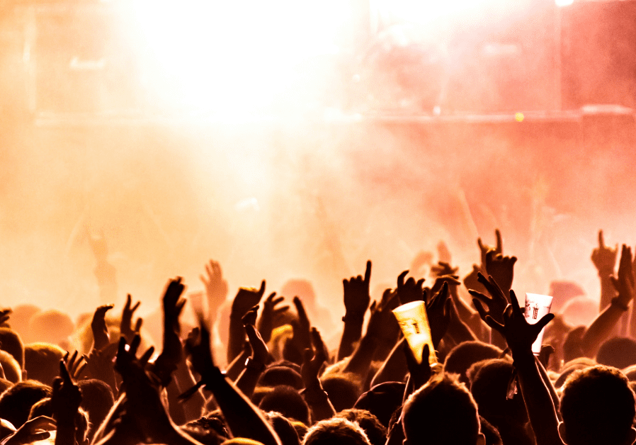 Large crowd of people at a live music concert in front of the stage.