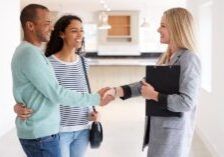 A couple shaking hands with a professional carrying a clipboard