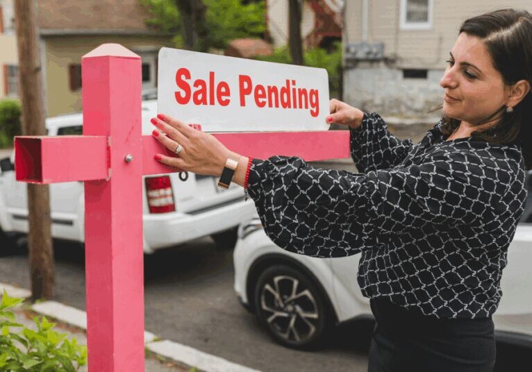 Image of a Realtor hanging a "Sale pending" sign