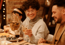 A man, woman, and child smiling while sitting around a holiday dinner table.