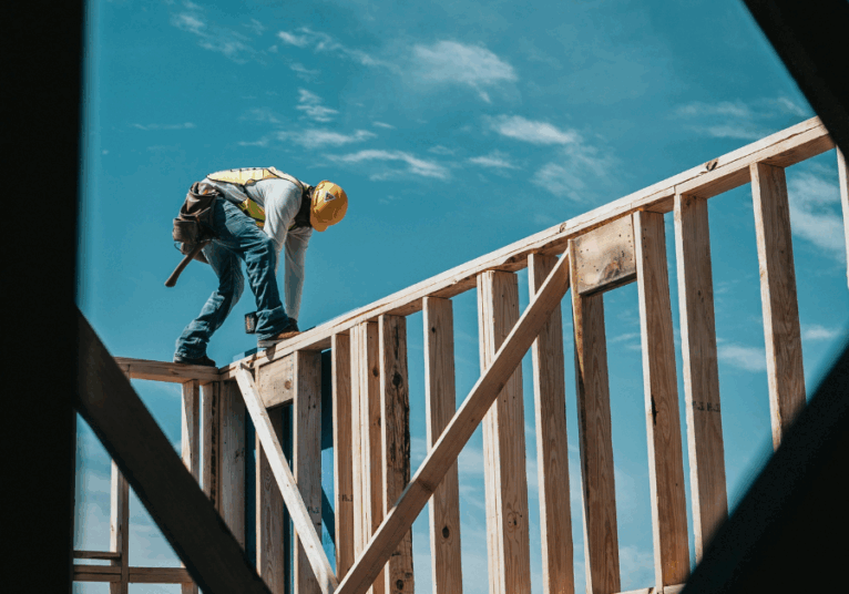 Image of a worker on top of the framing of a new construction home
