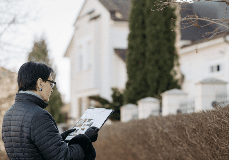 Woman holding a clipboard looking at a house for a property survey
