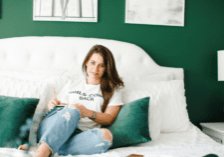 Jamie Milam sitting in her newly decorated room after divorce; the walls are green with white accents and posters hung up