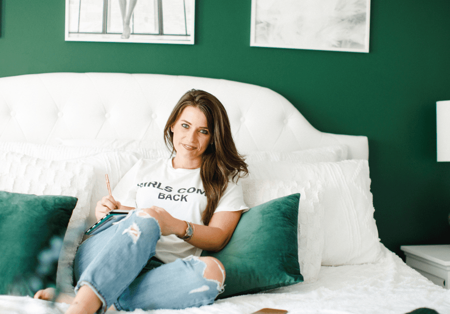 Jamie Milam sitting in her newly decorated room after divorce; the walls are green with white accents and posters hung up