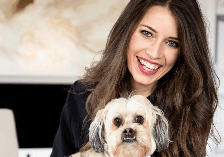 Image of Jamie Milam, a woman with dark hair, holding her pet dog